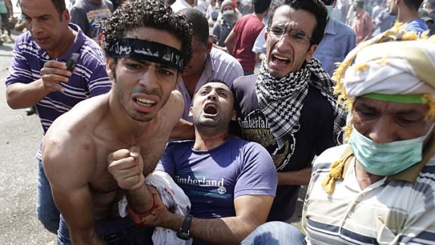 Supporters of Egypt's ousted President Mohamed Mursi carry a wounded man during clashes with Egyptian security forces in Ramses Square.