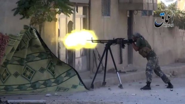 An Islamic State group fighter fires a heavy machine gun in Kobane.