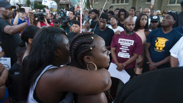 Kimberly Neal (braids) is embraced at a gathering in memory of her brother where he was shot and killed in Milwaukee, Wis. , Sunday, Aug. 14, 2016. Milwaukee Police shot and killed 23-year-old Sylville Smith near this spot on Saturday. Police in Milwaukee say a black man whose killing by police touched off arson and rock-throwing was shot by a black officer after turning toward him with a gun in his hand. (Mark Hoffman/Milwaukee Journal-Sentinel via AP)