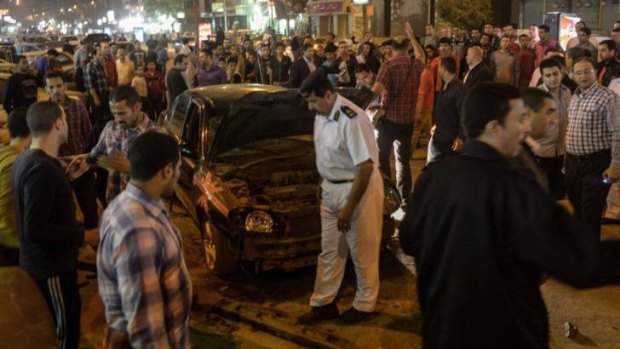 Fear on the streets: Egyptian security forces and bystanders inspect the wreckage of a car following a bomb attack in Cairo that left three civilians wounded on April 15.