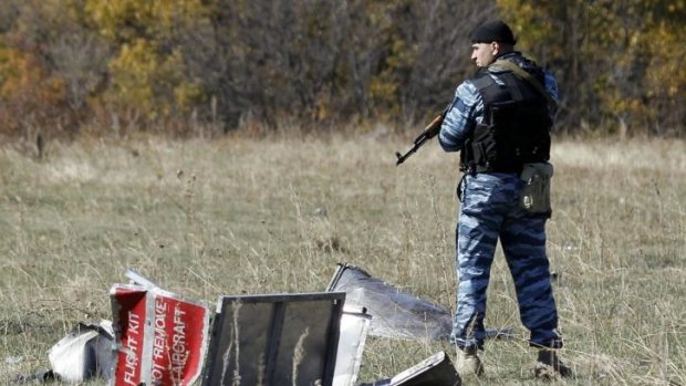 A policeman representing Donetsk People's Republic stands guard at the crash site of the downed Malaysia Airlines flight MH17, near the village of Grabovo.