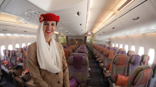 A steward poses at the economy class section of an Emirates aircraft.