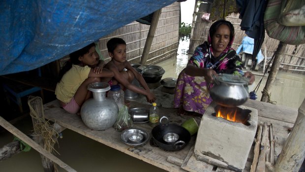 A woman prepares a meal in her flooded house at Sildubi village, in the northeastern Indian state of Assam.