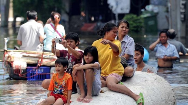 Afloat ... residents sit on a large piece of polystyrene foam during flooding in Bangkok