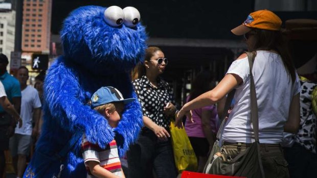 A person dressed in a Cookie Monster costume stands with a boy in Times Square.