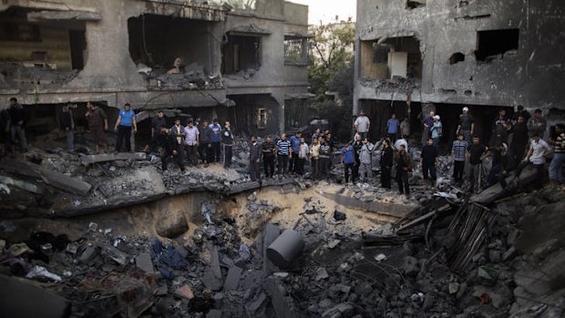 Palestinian men gather around a crater caused by an Israeli air strike on the Dallu family's home.