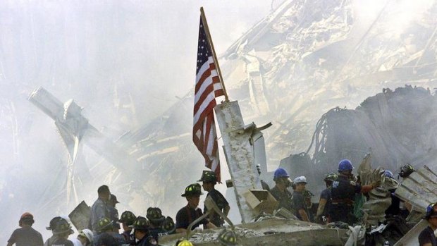 Iron to ash ... rescue crews, left, gather around a US flag on September 13, 200.