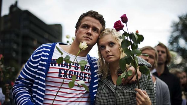 Paying their repsects ... a man and woman hold roses as thousands of people massed in Oslo.