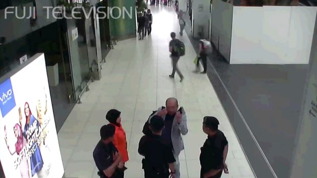 Kim Jong-nam, in grey, gestures towards his face while talking to airport security shortly before his death.