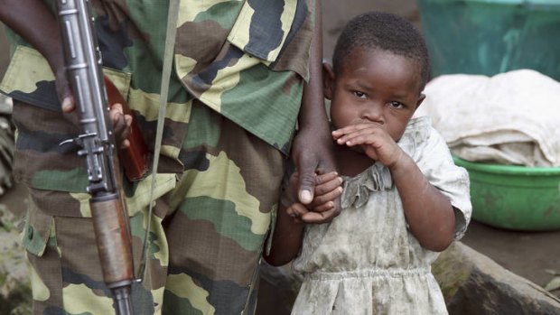 Divided ... a girl holds a hand of a M23 rebel fighter as the rebel groups prepare to withdraw from the town of Karuba, 60 kilometres west of Goma.