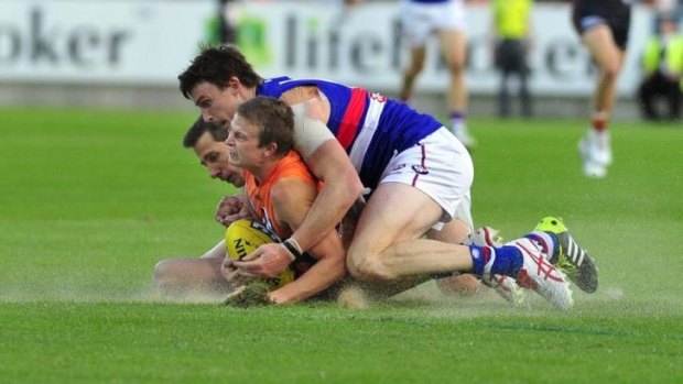 GWS Giants player Liam Sumner is brought down on the sandy Manuka surface in April's match against the Bulldogs.