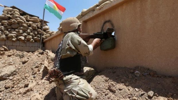A Kurdish peshmerga fighter takes his position behind a wall on the front line with militants from the Islamic State in Iraq and the Levant, in Tuz Khormato, 100 kilometres south of Kirkuk.