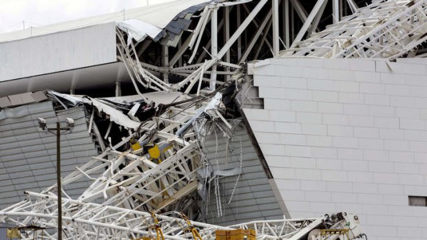 Workers stare at damages at the Arena de Sao Paulo --Itaquerao do Corinthians-- stadium, still under construction, after a crane fell across part of the metallic structure after a deadly accident.