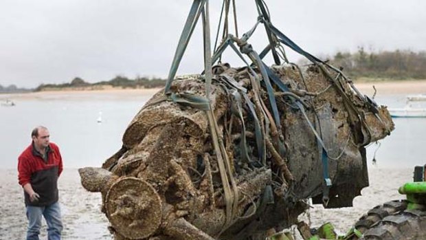 A crane lifts the upside down wreckage of Flight Lieutenant Henry 'Lacy' Smith's Spitfire from an estuary in North West France.