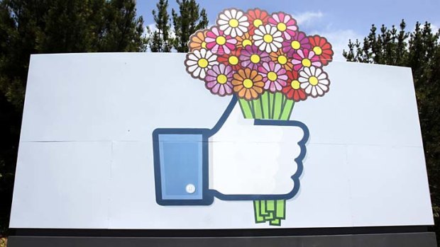 Flowers are added to a sign in front of Facebook headquarters in Menlo Park, California.