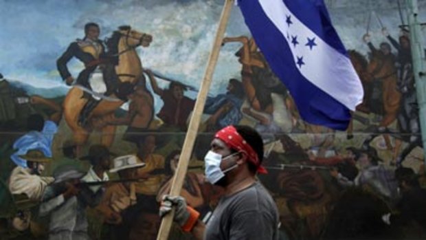 Pushed to the wall.. a supporter of ousted President Manuel Zelaya passes a mural during a protest.