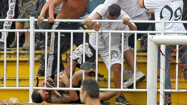 A fan of Vasco da Gama attacks a rival fan during a Brazilian Championship match in Joinville.