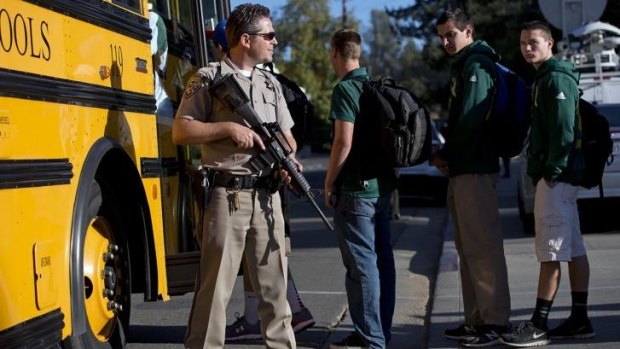A California Highway Patrol officer guards Placer High School students as they enter a bus following a lock down after the search for a suspect.