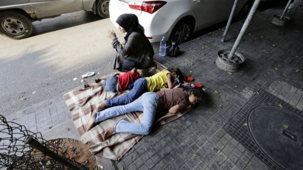 A Syrian woman sits next to her children sleeping on the street Beirut, Lebanon.