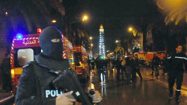 A hooded police officer prevents media from aproaching the scene of a bus explosion in the centre of Tunis on Tuesday.