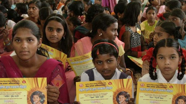 Almost 300 girls dressed in their best outfits sit with certificates stating their new official names during a renaming ceremony in Satara, India.