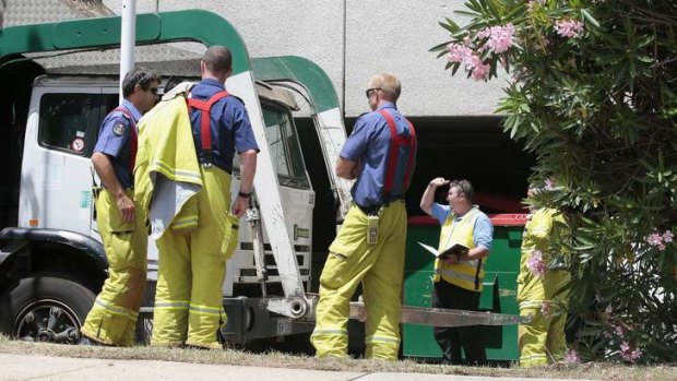 ACT Fire and Rescue member speaks with a ACT WorkSafe investigator at the scene of a fire in rubbish at the Hawker Soccer Club on Belconnen Way.