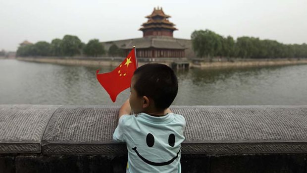 A young boy holds his country's flag: China is set to relax its one-child policy.