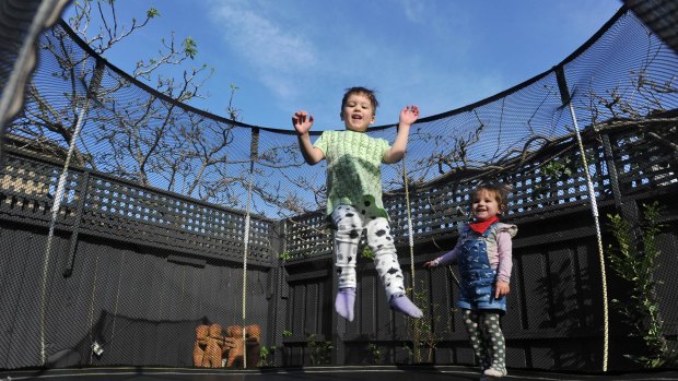 Three-year-old Rafael Boehmer and her one-year-old sister Esmeralda Boehmer play on a backyard trampoline. 