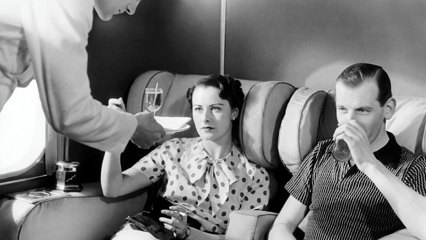 A couple enjoys cocktails in the smoking lounge of a plane in London during the 1930s.