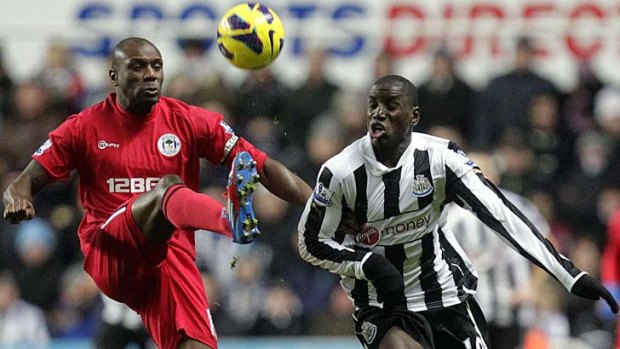 Newcastle United striker Demba Ba vies with Wigan defender Emmerson Boyce at St James Park.