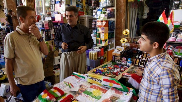 A salesman in Irbil's bazaar selling patriotic and pro-independence ware talks with a customer in Irbil, Iraq. 