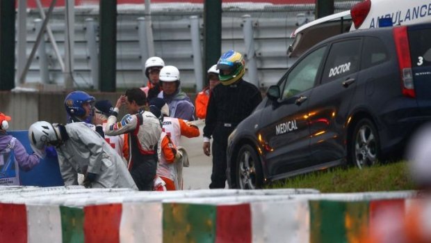 A distressed Adrian Sutil, centre, of  Sauber F1 speaks to a doctor while Jules Bianchi of Marussia receives urgent medical attention following a crash.