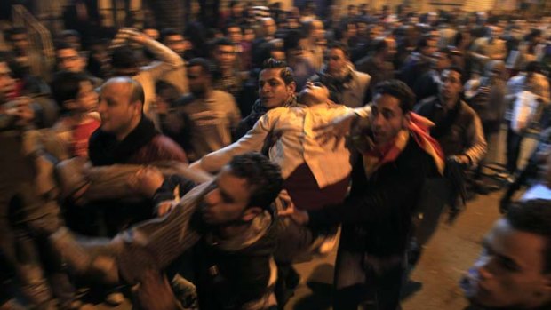 Protesters out in force ... a man affected by tear-gas is carried to safety during clashes with police in downtown Cairo.