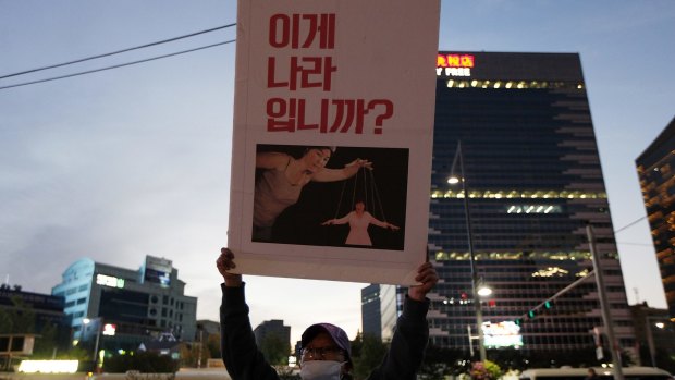 A protester holds a placard showing South Korean President Park Geun-hye as a puppet with the words "This is not a country."