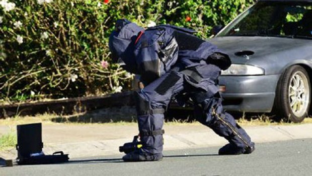 A bomb squad officer inspects the pipe bomb found at Redbank Plains on Tuesday. Photo: David Nielsen, Queensland Times