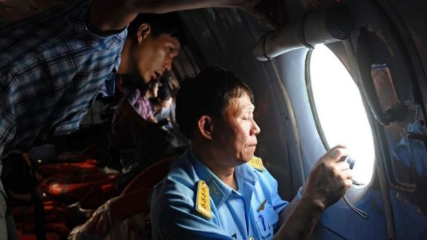 A Vietnamese officer (right) and a reporter looking out the window during search operations over the southern seas off Vietnam.