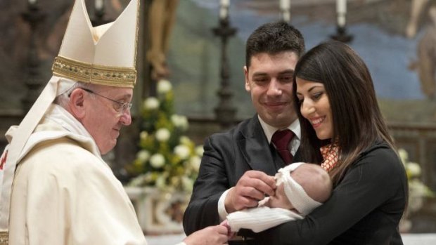 Pope Francis baptises one of 32 babies during a mass in the Sistine Chapel at the Vatican.