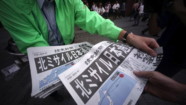 A man, left, distributes an extra edition of a newspaper reporting about North Korea's missile launch, at Shimbashi Station in Tokyo.