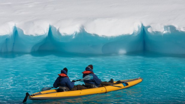 Kayak through an ice slushy among icebergs in Antarctica.