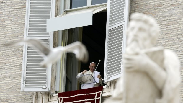 Pope Francis is given a piece of paper as he prepares to deliver the Angelus prayer from his studio's window overlooking St Peter's Square, at the Vatican on Sunday.