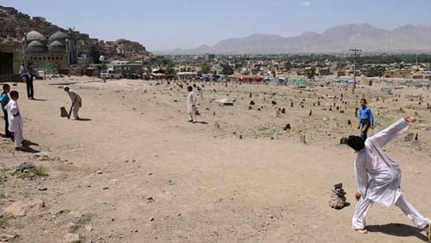 Afghan boys play cricket near a cemetery in Kabul.