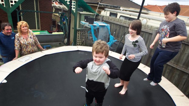 Rowhan, Paige and Roy bounce on the trampoline watched by Paul and Penny Matthews.