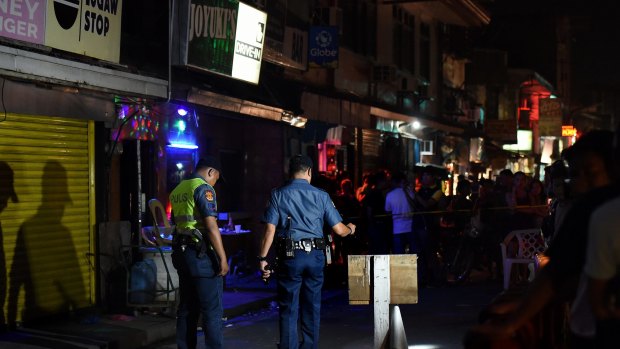 Police at the scene of a double shooting in the Manila suburb of Baclaran, where two masked gunmen shot dead two men aged 21 and 35 who were drinking in a bar.