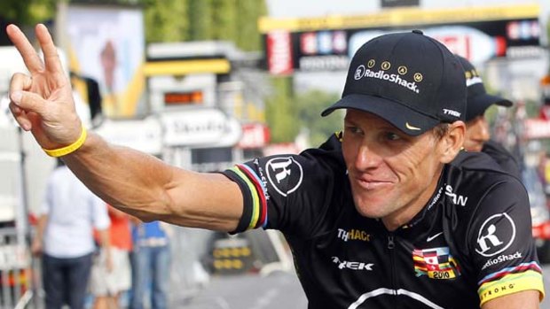 Lance Armstrong waves on the Champs Elysees wearing a special 'Livestrong' jersey.