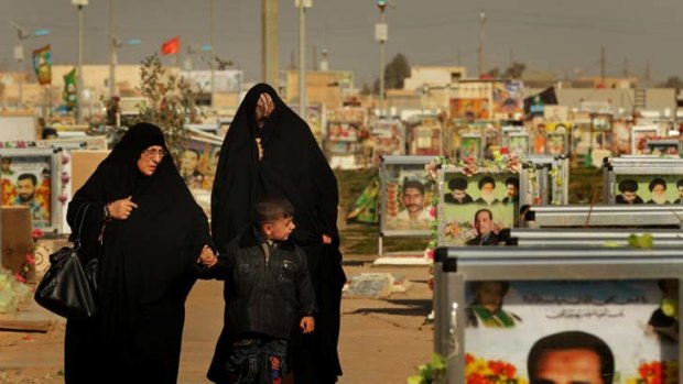 With respect &#8230; a family walks past graves at the Shiite militia 'Mahdi cemetery' section at Wadi Al-Salam, among the holiest of burial places for Shiite Muslims.