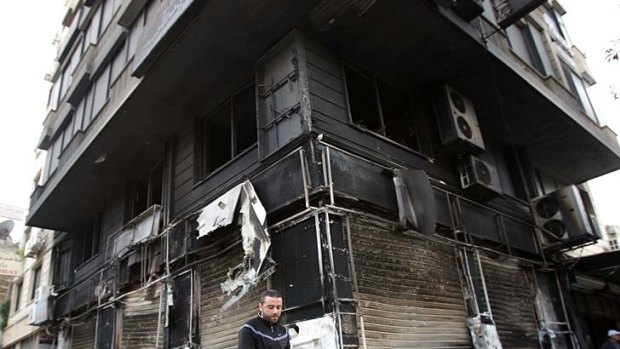 Terror on the streets ... a man walks past a burnt out building in Latakia.