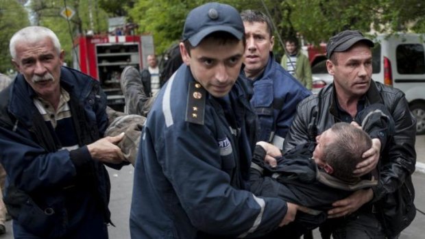 Police and citizens carry a firefighter injured during an attack on a police station in Mariupol, eastern Ukraine.
