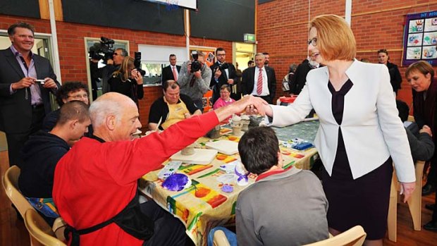 Hands across the table: Julia Gillard with Richard Kindred at a community access program in Tasmania.