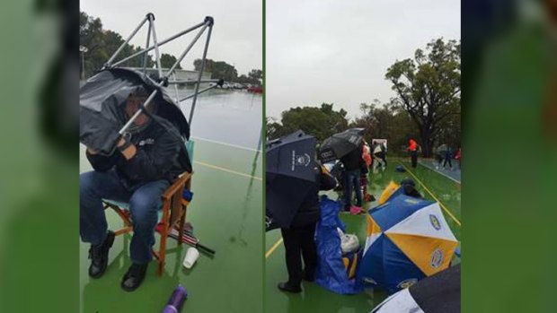 Spectators take cover at the netball on Saturday as youngsters are forced to play on.