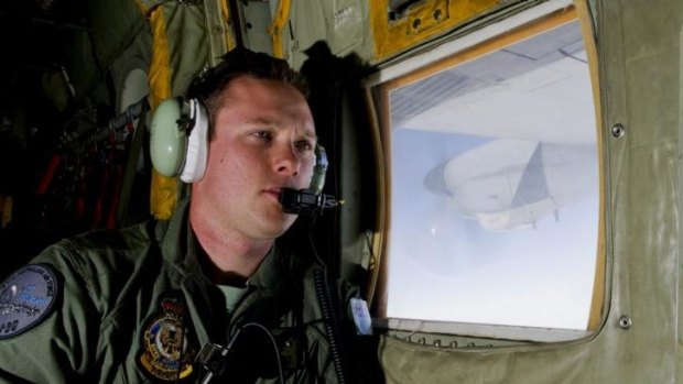 Using spotters to track debris ... RAAF Loadmaster Sergeant Adam Roberts scans the southern Indian Ocean on board a C-130J Hercules. 